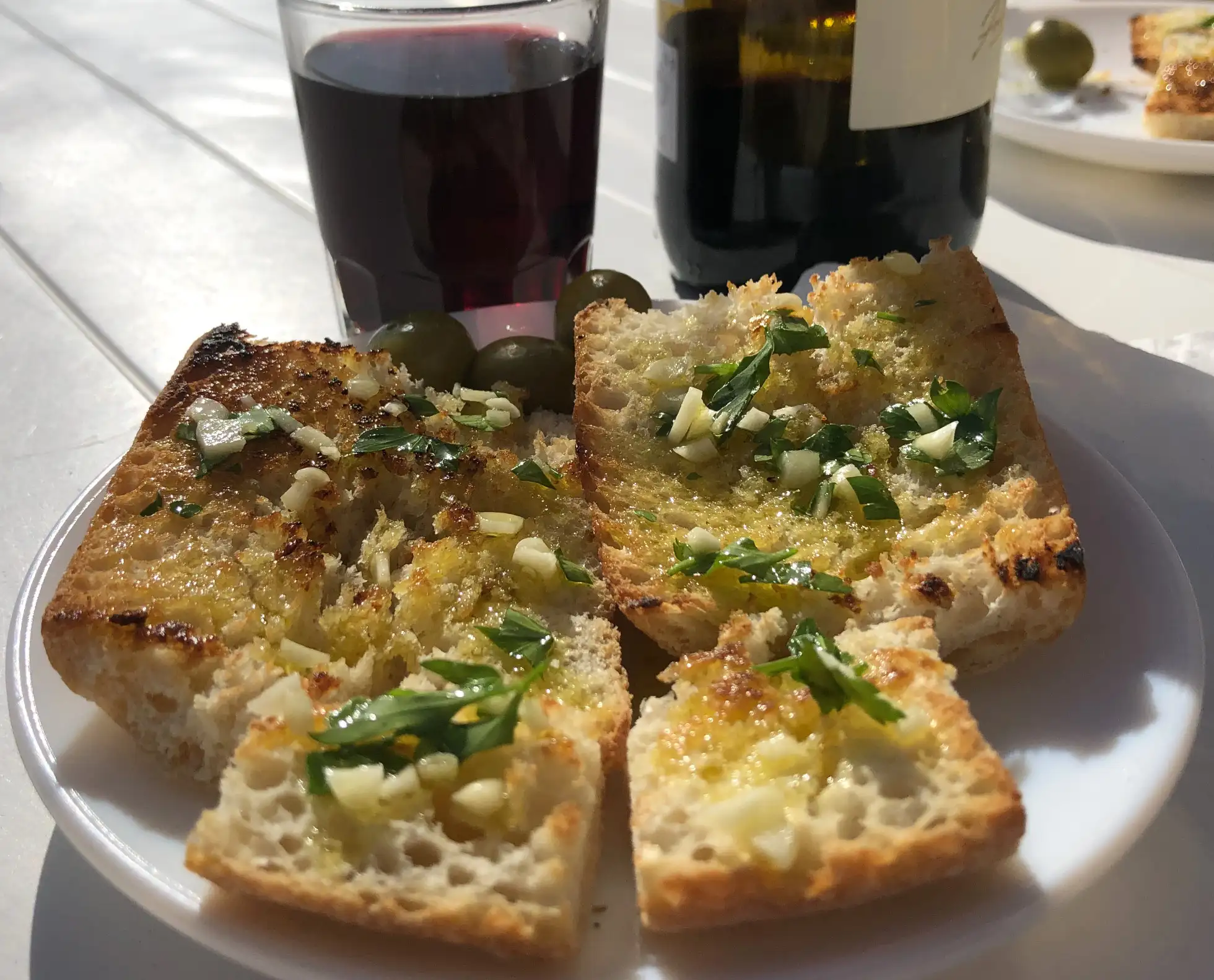 Aceite de oliva, ajo y perejil sobre pan blanco tostado” style=